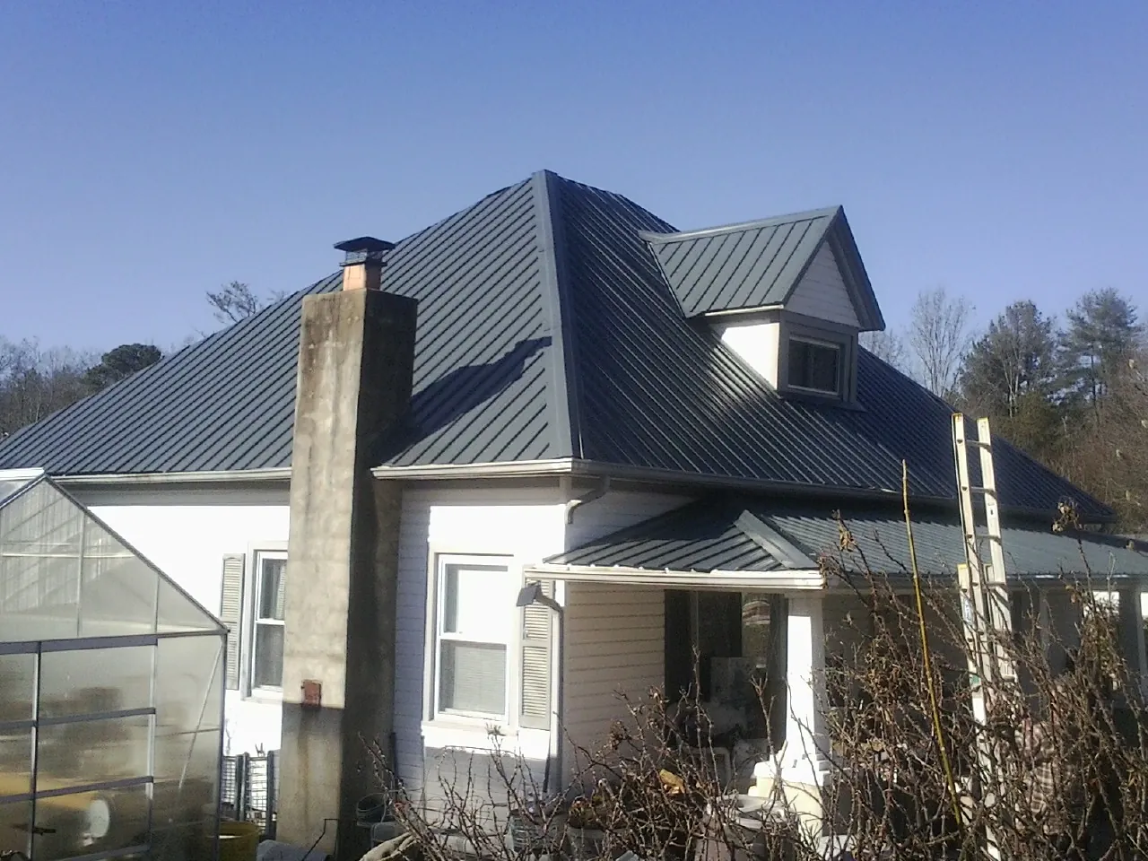 Dark blue standing seam metal roof on a white farmhouse with dormer — Slate & Tile Roof Repair by Roofing Brothers in Rock Tavern
