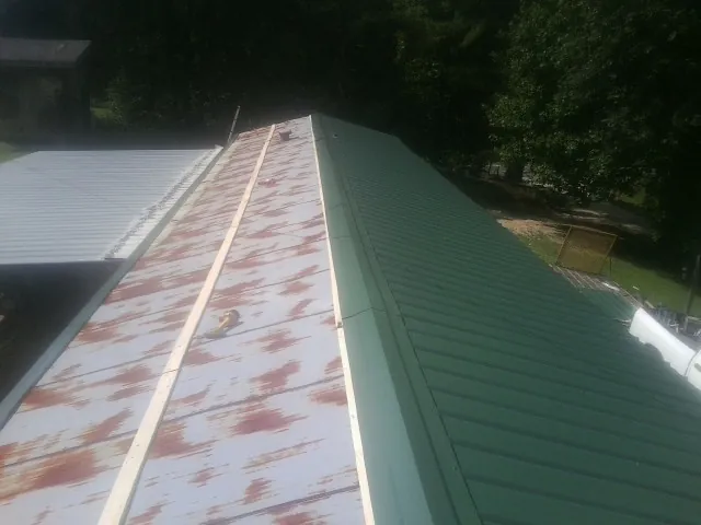 Old rusted panels beside newly installed green metal roofing — Wind Damage Roof Repair by Roofing Brothers in Rock Tavern