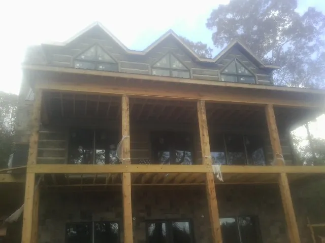 Dormers and porch framing on a large log home under construction — Roof Coating work by our crew in Rock Tavern