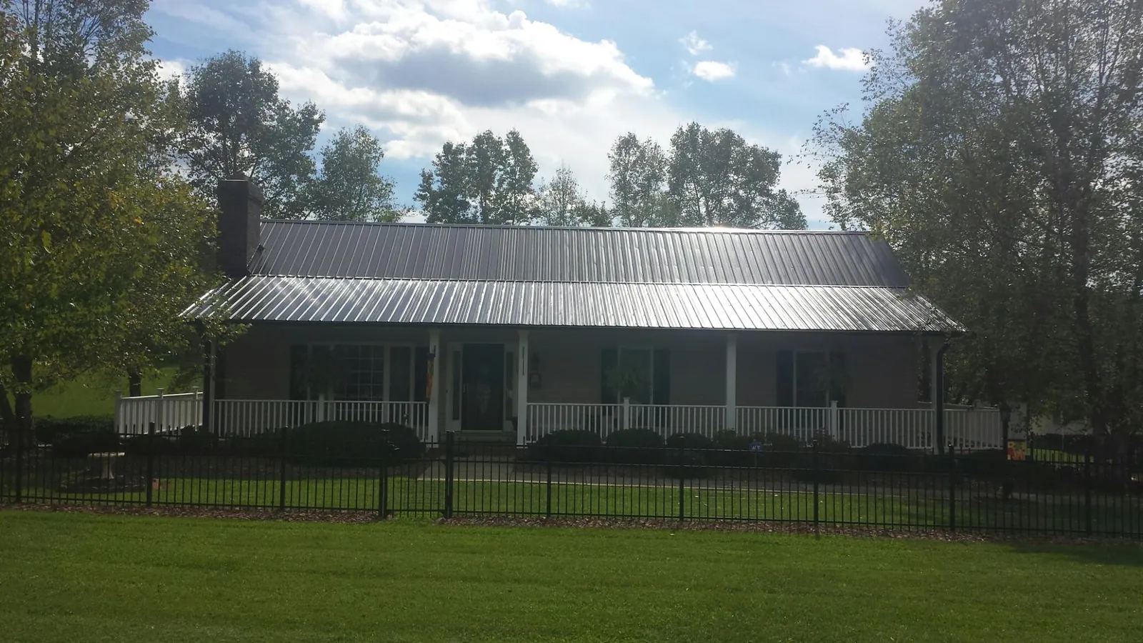 Gray metal roof on a brick ranch with a full width front porch — Gutter Guard Installation work by our crew in Rock Tavern