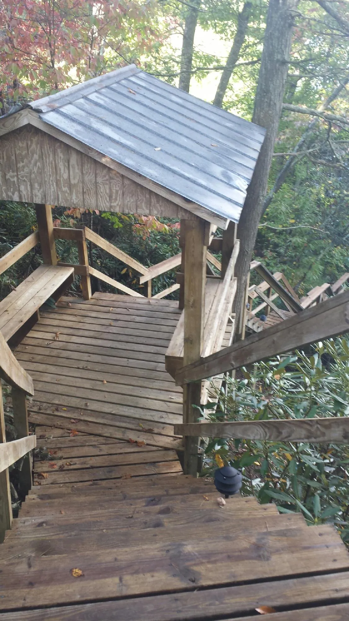 Metal roofed shelter over wooden steps on a wooded walkway — Skylight Repair & Installation work by our crew in Rock Tavern