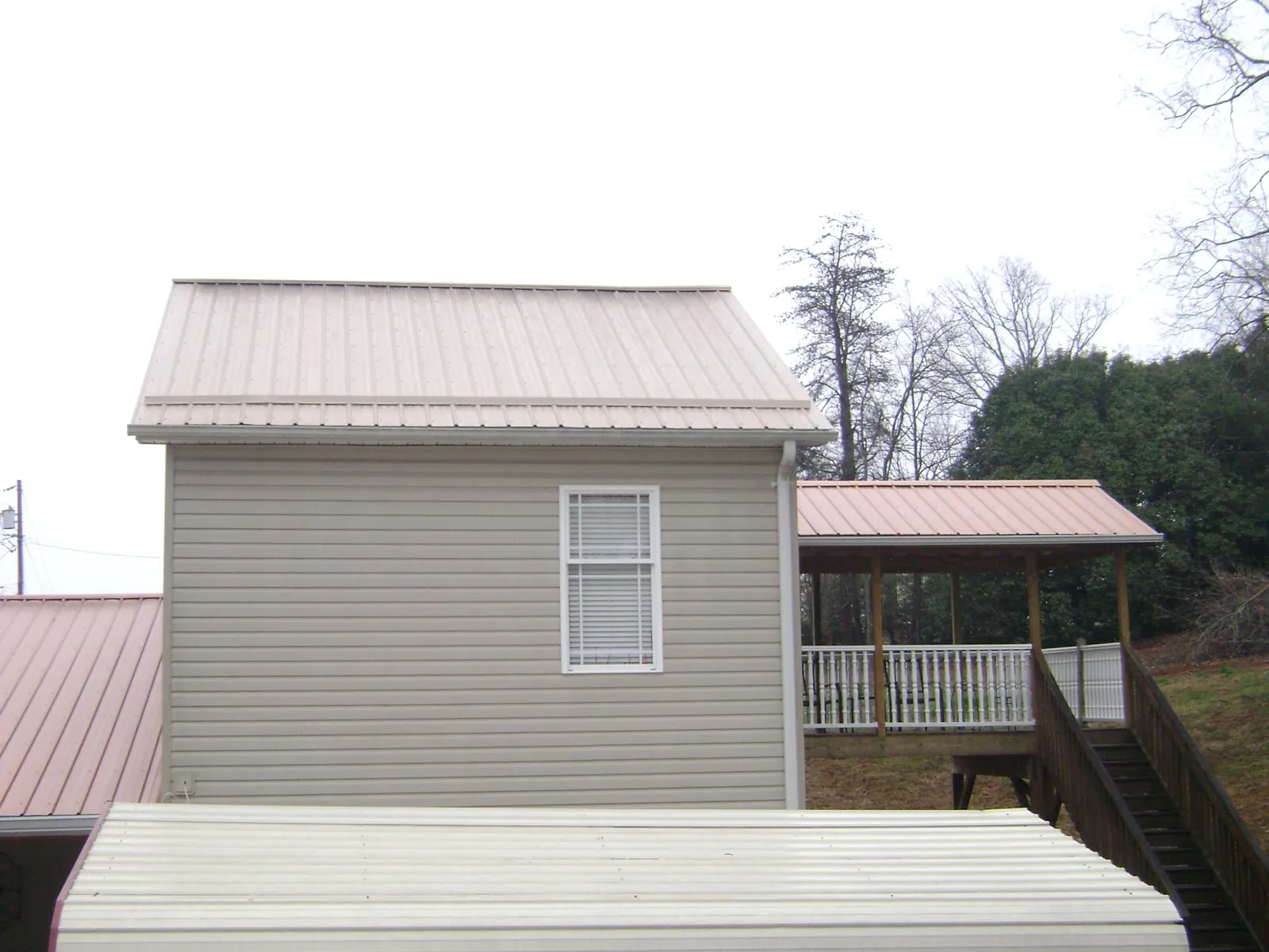 Tan metal roofs on a two story addition and attached porch, from a Roof Replacement job in Rock Tavern