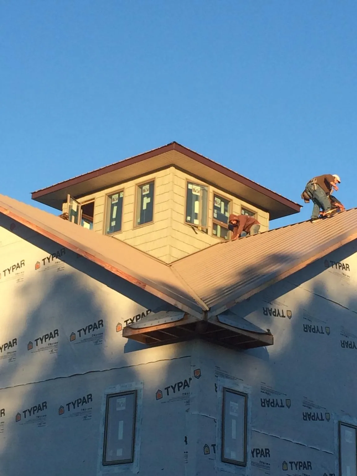 Roofers working around a rooftop cupola on a new metal roof at sunset — Roof Waterproofing in Rock Tavern by Roofing Brothers